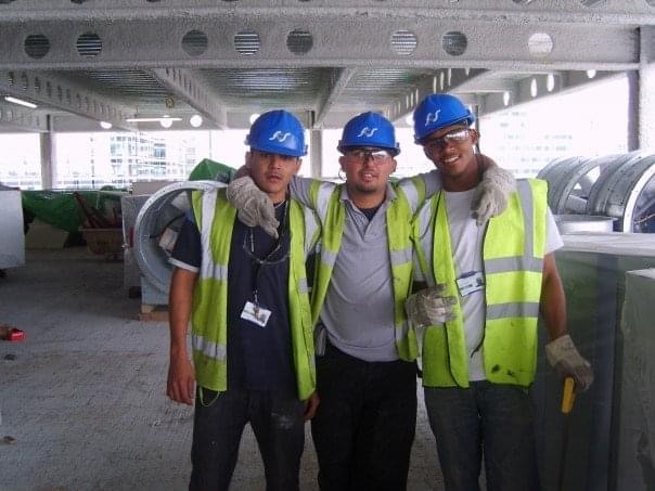 Early-career site crew in hard hats and high-visibility vests on a London building project